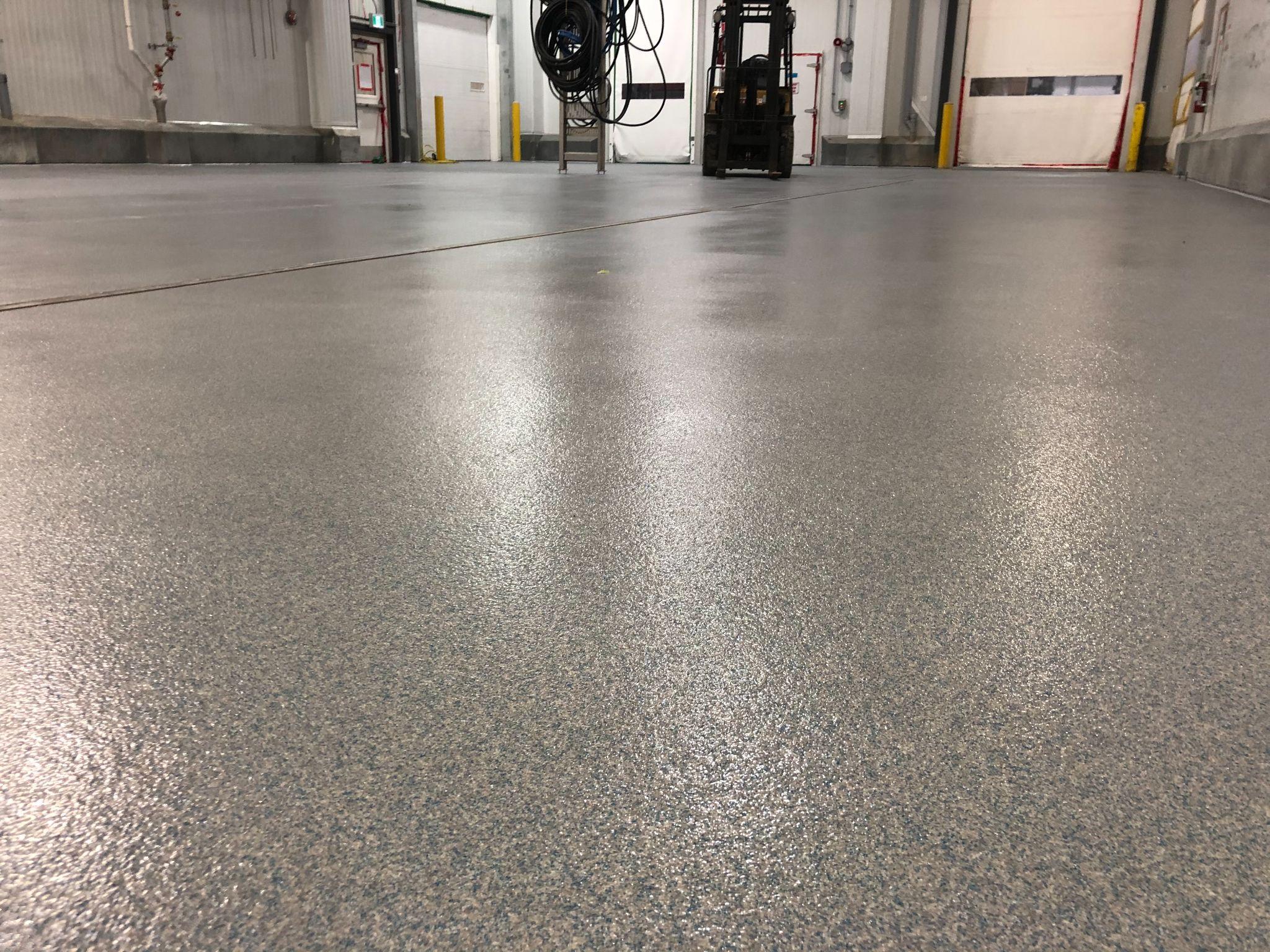 Textured grey epoxy floor in an industrial facility with a forklift in the background